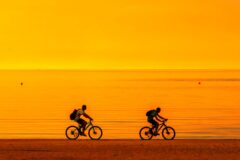 couple on a sunset bike ride on the beach