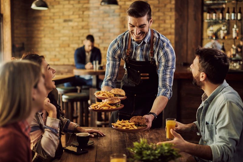 Waiter serving burger orders to a group of friends. 